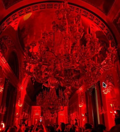 Galería palaciega iluminada en rojo con lámparas monumentales